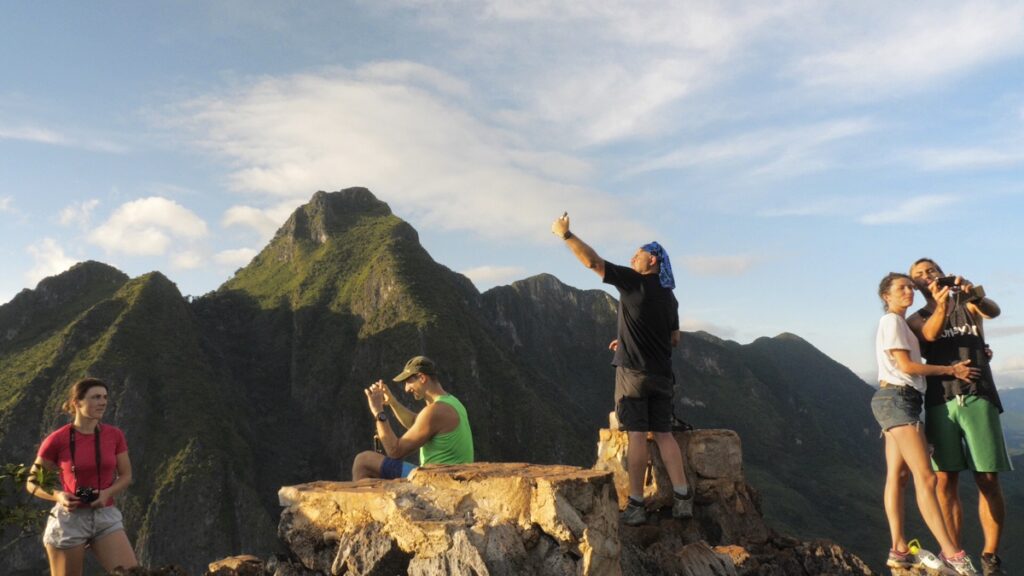 tourists take selfies while atop a mountain